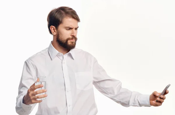 Hombre guapo con vaso de agua estilo de vida saludable camisa blanca fondo claro — Foto de Stock