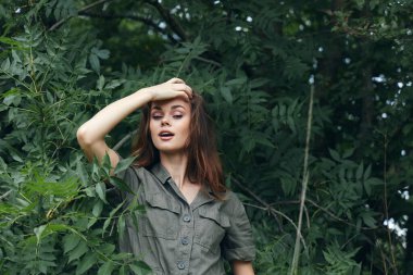 Ormandaki kadın, ağzı açık, yaz mevsiminde elini başının üstünde tutuyor. 