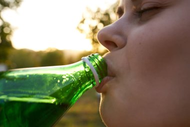 Bahçe manzaralı mutlu kadın bir şişe suyla davetiye bekliyor.