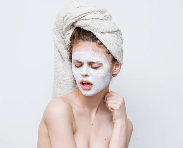 Çıplak omuzlu, başı havluyla cilt bakımı maskeli bir kadın. — Stok fotoğraf