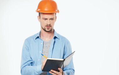 Turuncu şapkalı inşaat mühendisi elinde belgelerle iş yapıyor.
