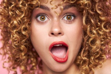 Kıvırcık saçlı kadın açık ağızlı, parlak makyajlı. 