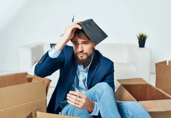 Business man with boxes sits on the office floor unpacking things