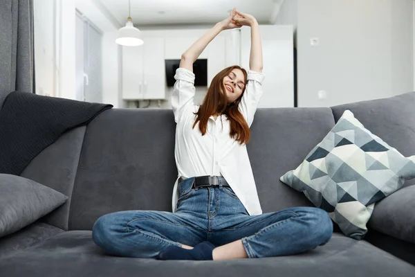 Kvinna som håller händerna över huvudet Sitter på soffan — Stockfoto