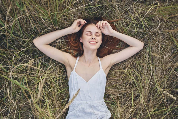 Mujer feliz se encuentra en la hierba seca y gestos con sus manos vestido blanco Copiar espacio —  Fotos de Stock