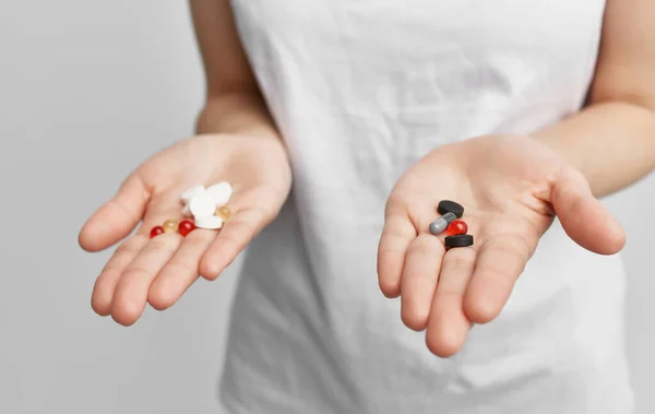 Morena en una camiseta blanca con pastillas en las manos problemas de salud — Foto de Stock