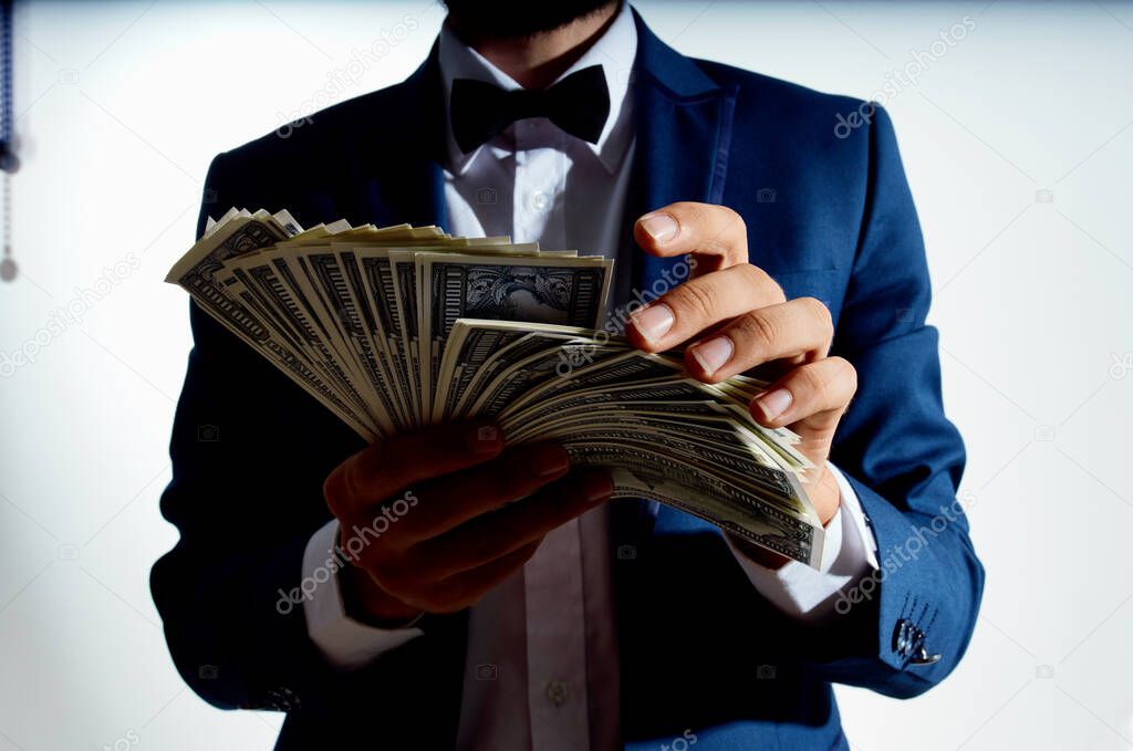 rich guy with a bundle of big money and in a classic suit on a light background