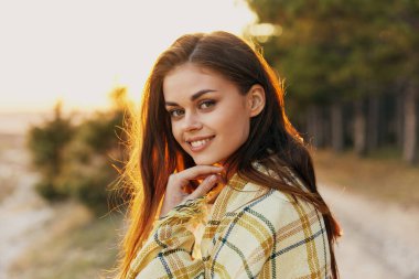 Mutlu kızıl saçlı kadın gün batımında omuzlarında kareli ekoseyle