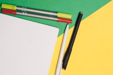 Ofis, sarı yeşil arka planda kalem ve not defteri temin ediyor.
