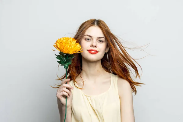 Mulher sorridente lábios vermelhos flor amarela em mãos de modelo de presente charme — Fotografia de Stock