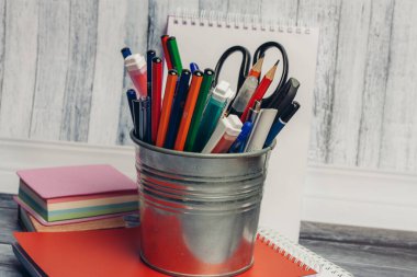 Tahta bir masa ve kırmızı bir defter üzerinde demir kumaş kırtasiyesi.