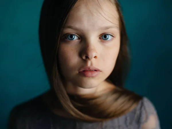 Portrait d'une belle petite fille en robe grise sur fond bleu vue rapprochée du modèle — Photo