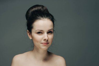 Gri arka planda suratını buruşturan güzel bir kadın.