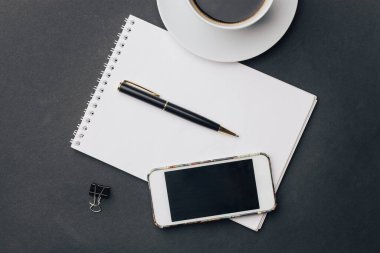 Kalem bardağı telefon teknolojisiyle birlikte çalışma masası not defteri.
