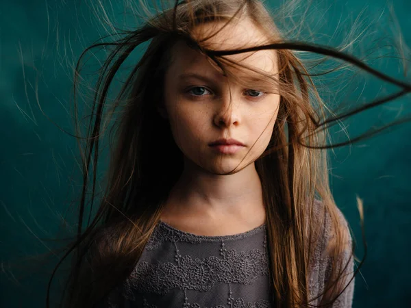 Hübsches kleines Mädchen mit zerzausten Haaren auf türkisfarbenem Hintergrund — Stockfoto