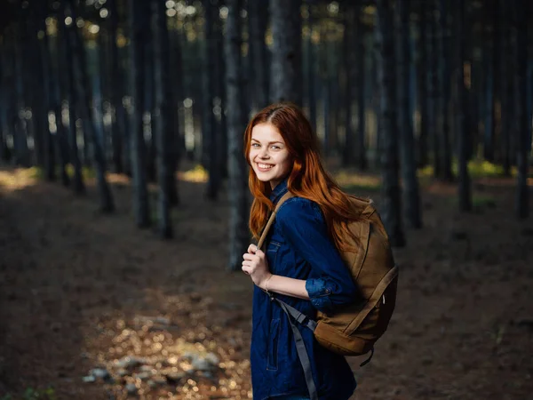 Mujer feliz excursionista en el bosque con una mochila en su espalda en otoño en la naturaleza —  Fotos de Stock