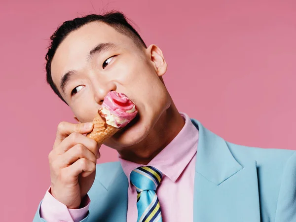 ピンクの背景のコーンにアイスクリームを入れたスーツの男 — ストック写真
