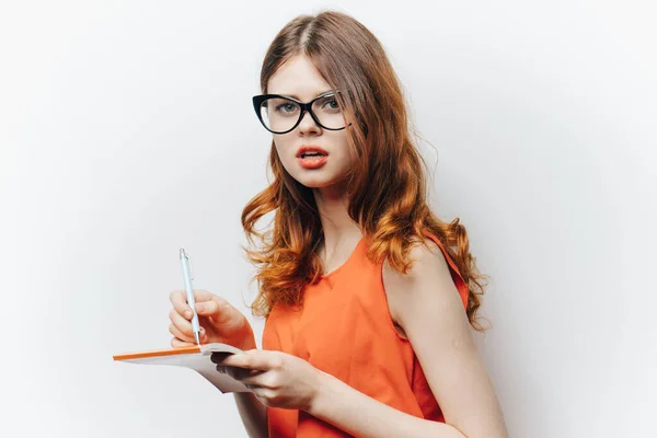 Vrouw in oranje shirt met notitieblok in handen mode bril — Stockfoto