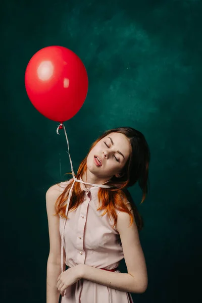 Kvinna på en grön bakgrund håller en heliumballong i handen och helgdagar födelsedag — Stockfoto