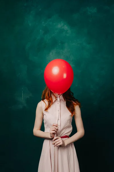 ピンクのドレスで顔の前に赤いボールを持つ女性クロップドビュー — ストック写真