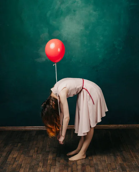 Mujer alegre con una bola roja en la mano doblada sobre un fondo verde —  Fotos de Stock