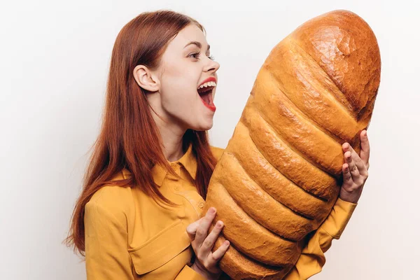 Mujer sorprendida examina un pan en sus manos sobre un fondo claro —  Fotos de Stock