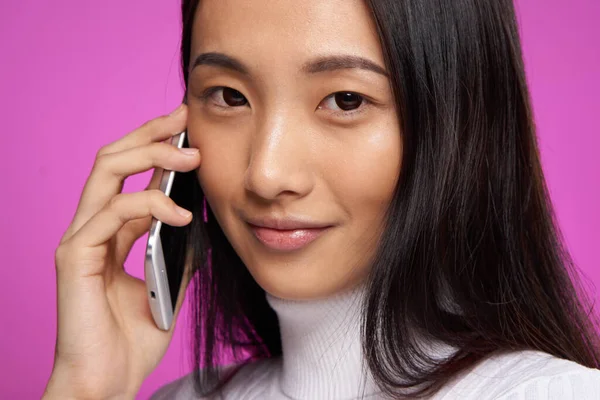 Гарна жінка азіатський зовнішній вигляд технологія телефонного зв'язку крупним планом рожевий фон — стокове фото