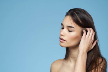 Çıplak omuzlu, uzun saçlı, kozmetik ürünleri olan bir kadın.