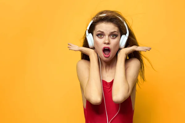 Mujer alegre en auriculares escucha música en un fondo amarillo camiseta roja —  Fotos de Stock