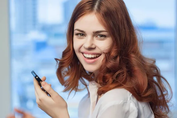 Rothaarige Frau mit Telefon in der Hand im Büro-Technik-Profi — Stockfoto