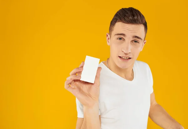 Joven sobre un fondo amarillo sostiene una tarjeta de crédito en su mano y Copiar espacio — Foto de Stock