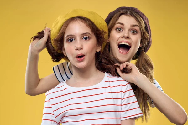 Irmãs alegres em chapéus listrado T-shirts alegria estilo de vida amarelo fundo família — Fotografia de Stock