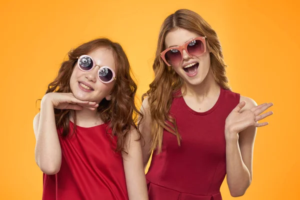 Joyeuse maman et fille portant des lunettes de soleil style de vie amitié famille jaune fond studio — Photo