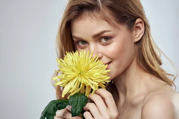 Porträtt av en vacker kvinna med en gul blomma på en ljus bakgrund charmigt leende modell rött hår — Stockfoto