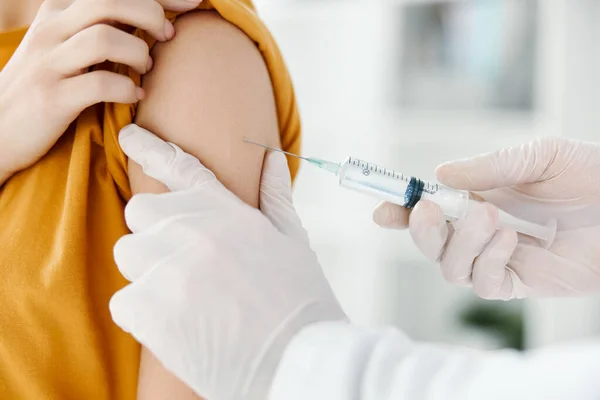 Médico inyecta una vacuna en el hombro de una paciente mujer con una máscara médica en una vista lateral del hospital —  Fotos de Stock