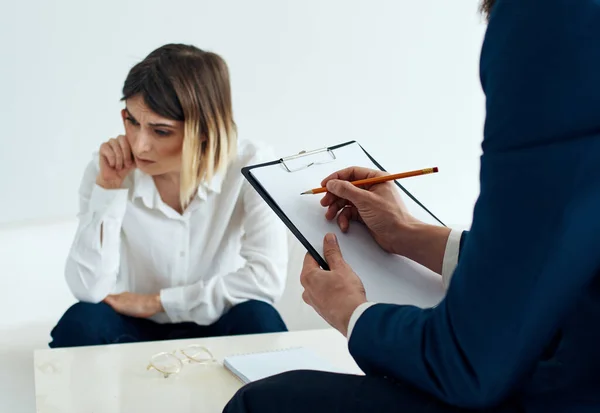 Un uomo in abito classico con documenti in mano e una donna emotiva sul divano — Foto Stock