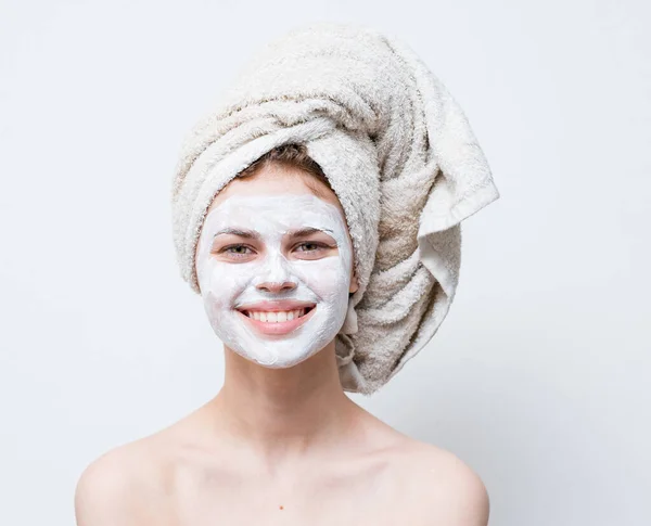 Kobieta dba o swój wygląd i ręcznik na głowie i krem nawilżający na twarzy — Zdjęcie stockowe