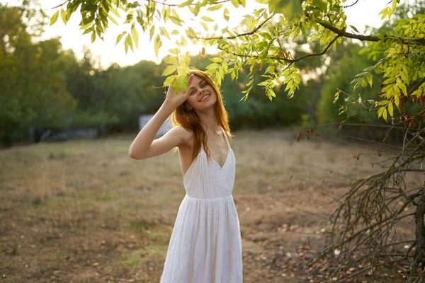 Yeşil yaprakların yanında doğa elbisesi içinde mutlu bir kadın. Arka planda ağaçlar ve çalılar var. — Stok fotoğraf