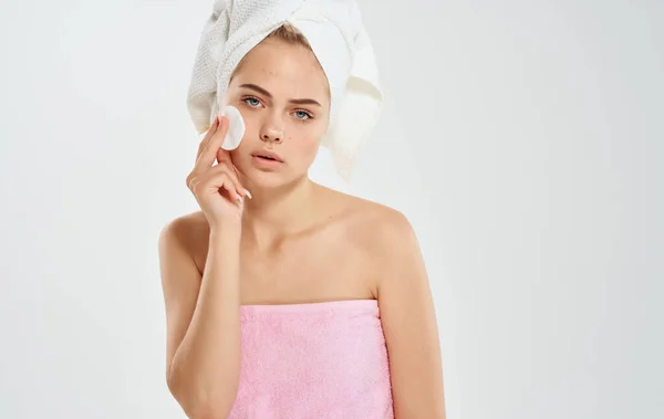 Γυναίκα σε ροζ πετσέτες χρησιμοποιώντας περιποίηση προσώπου δέρμα σε γκρι φόντο χέρι — Φωτογραφία Αρχείου