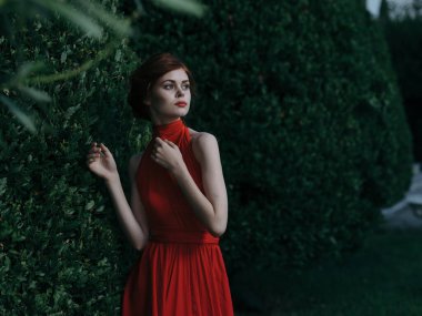 Güzel kadın kırmızı elbise kozmetik çekici yeşil çalı karnavalı