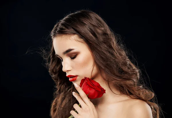 붉은 장미를 손에 들고 어두운 배경을 클로즈업 한 브루넷 여성 — 스톡 사진