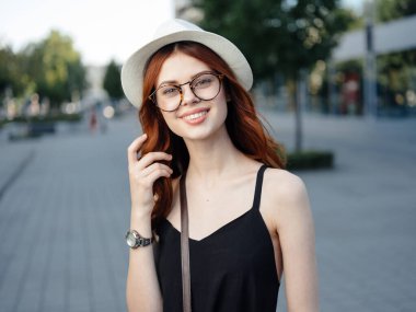 çekici bir kadın sokakta yürüyor şapka ve gözlük takıyor.