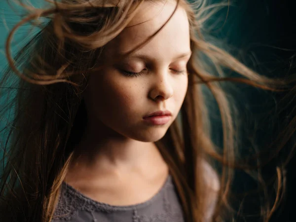 Retrato de uma menina bonita com olhos fechados em um fundo turquesa e cabelo solto — Fotografia de Stock