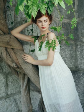 Beyaz elbiseli kadın dışarıda yeşil yapraklar yakın plan temiz hava.