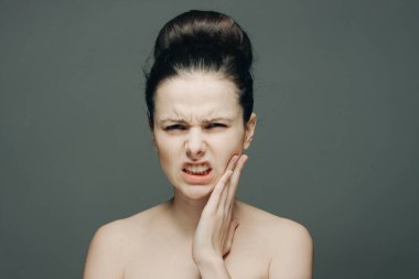 Esmer hoşnutsuz yüz ifadesi yüzünü gri arkaplanda tutuyor.