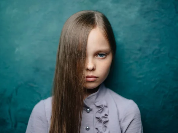 Okouzlující dívka s volnými vlasy na tyrkysovém pozadí v šedých šatech — Stock fotografie