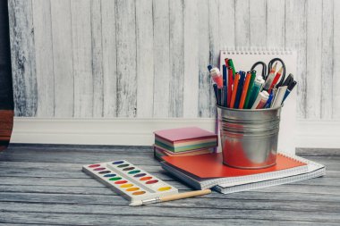 Kalemli demir cam, makas, keçeli kalem ve tahta masa suluboya boya üzerine not defteri.