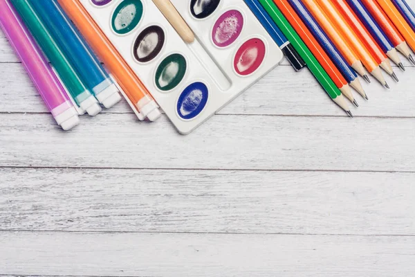 Lápices de colores acuarela pinturas y rotuladores plumas en la educación de la escuela de mesa de madera — Foto de Stock