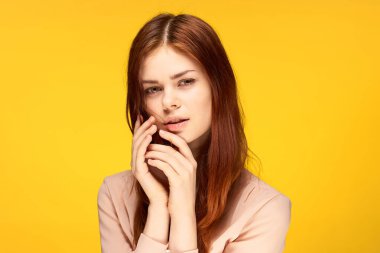 Güzel bir kadın, çekici. Duygularına bak. Yüzü sarı arka plana yakın.