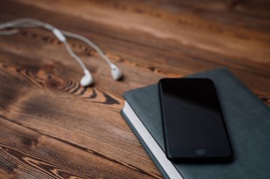 defter ahşap masa telefonu ve kulaklıklar.